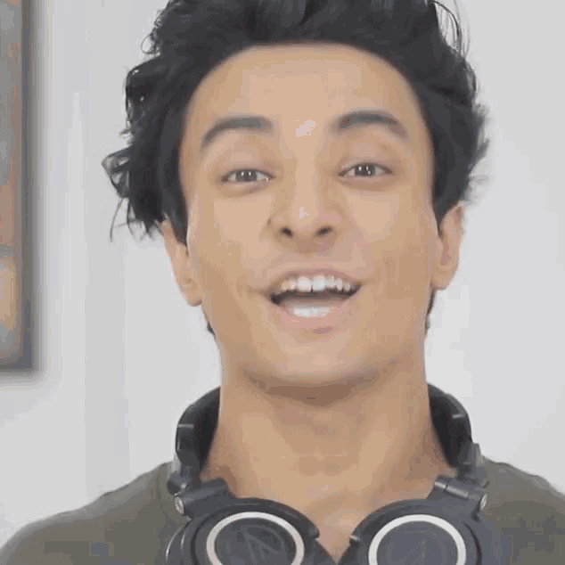 a man with headphones around his neck is smiling and looking at the camera