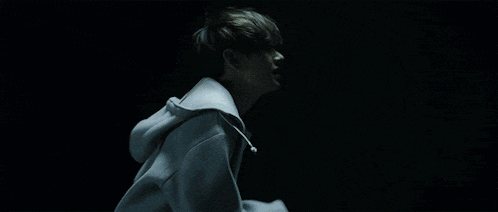 a person in a white hoodie is walking in the dark .