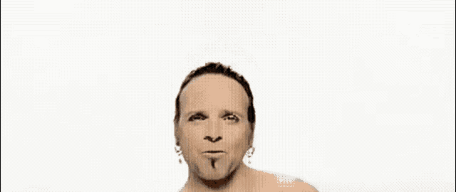 a naked man with a piercing in his ear is making a funny face .