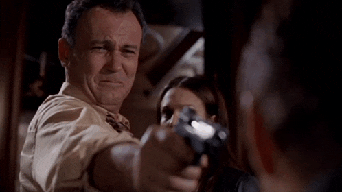 a man is pointing a gun at a woman who is tied up
