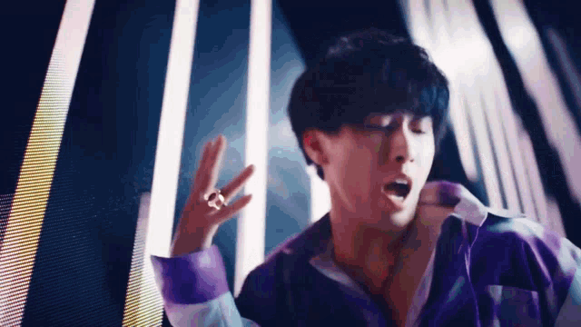 a man in a purple shirt is singing into a microphone while dancing