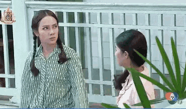 two women standing next to each other in front of a fence with the number 7 on the screen
