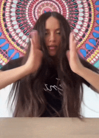 a woman with long hair is making a funny face in front of a colorful painting
