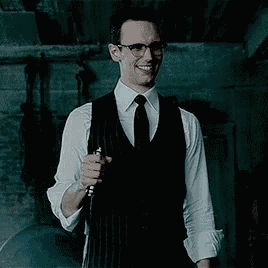 a man in a suit and tie is holding a knife in his hand in a dark room .