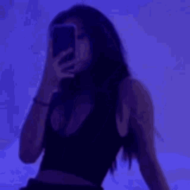 a woman is taking a picture of herself with her phone in a dark room .