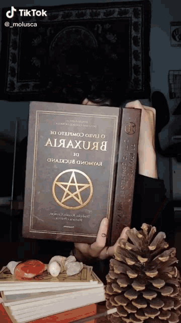 a person is holding a book with a pentagram on the front
