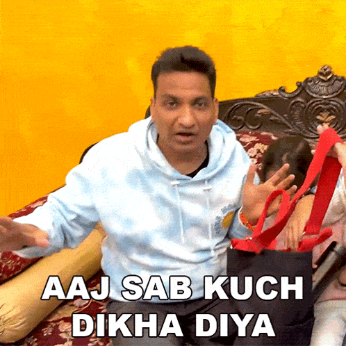 a man is sitting on a bed holding a red bag with the words aaj sab kuch dikha diya written on it