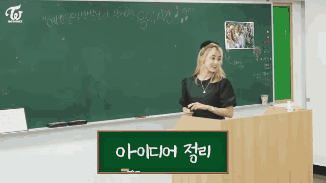 a woman stands at a podium in front of a blackboard with twice on it