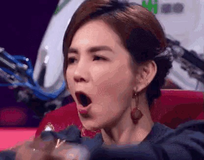 a woman is sitting in a chair with her mouth open and making a funny face .