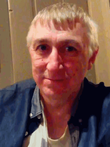 a man with gray hair and a blue shirt is smiling