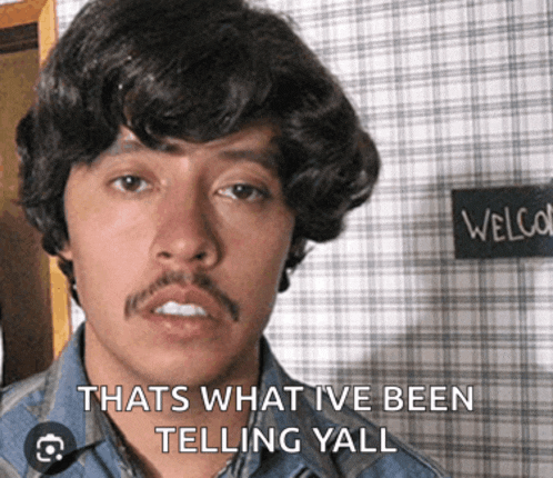 a man with a mustache is standing in front of a sign that says welcom