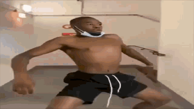 a shirtless man wearing a mask is standing in a hallway .