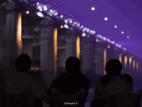 three people are standing in a dark room with purple lights behind them ..