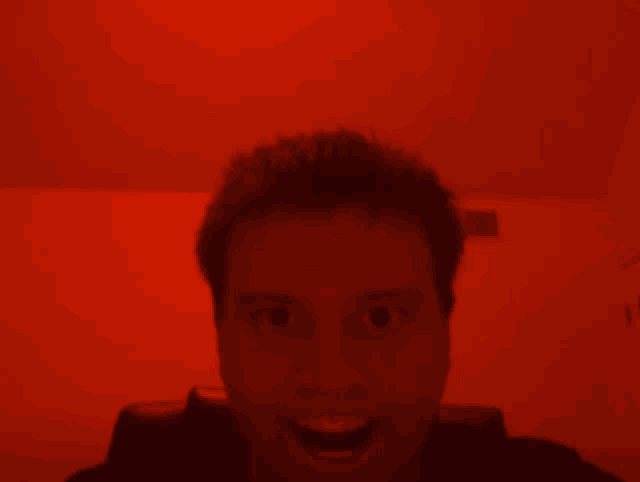 a man is smiling in a red room