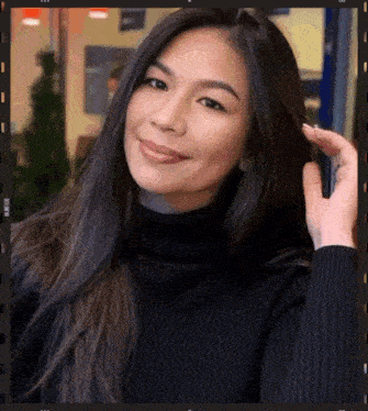 a woman wearing a black turtleneck sweater is smiling for the camera