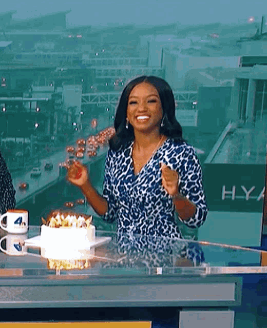 a woman in a blue and white leopard print dress is standing in front of a cake