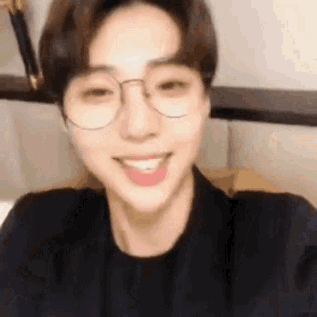 a close up of a young man wearing glasses and smiling .