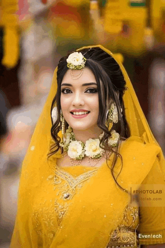 a woman in a yellow dress with flowers in her hair is smiling for the camera