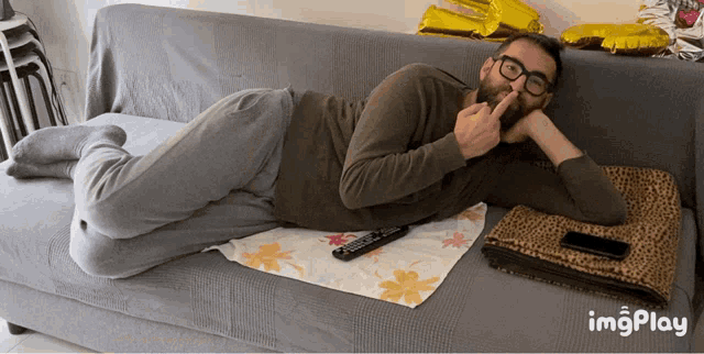 a man laying on a couch with a remote control in front of him and the word imgplay below him
