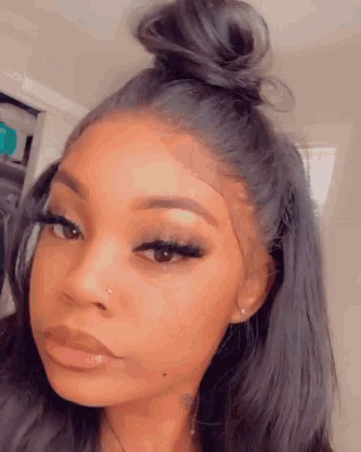 a close up of a woman 's face with a bun on her hair