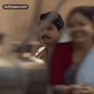 a man with a mustache is standing next to a woman in a room .
