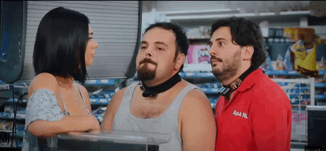 a man in a red shirt that says ' bam ' on it stands next to two other men