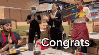a woman holding a sign that says happy birthday congrats