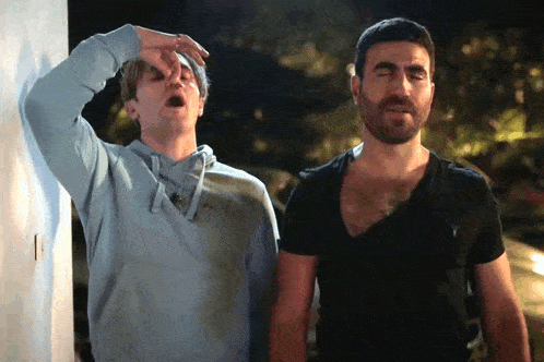 two men are standing next to each other one has his hand on his nose and the other has his eyes closed