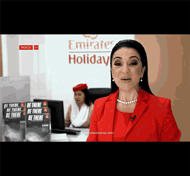 a woman in a red jacket is standing in front of a emirates holiday sign