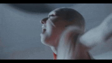 a close up of a person 's face with a red scarf around their neck in a dark room .