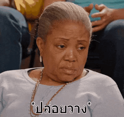 a woman in a blue shirt has a necklace around her neck and a foreign language written on her face
