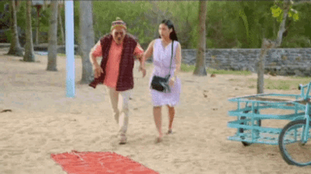 a man and a woman are walking on a beach next to a bicycle .