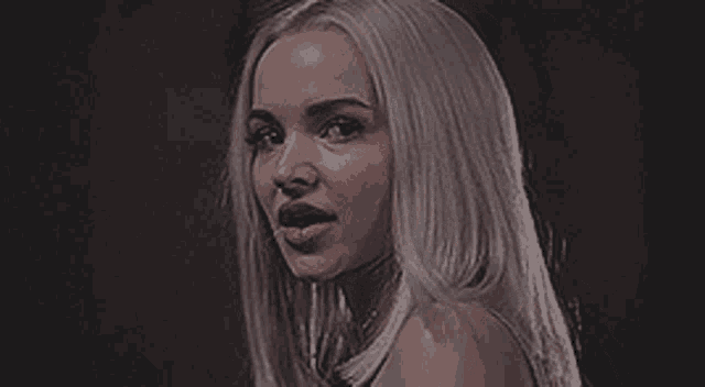a woman with long white hair is holding a pair of boxing gloves in her hand .