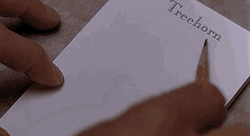 a person is writing on a piece of paper that says treehorn on it .