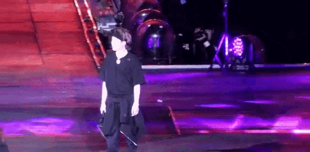 a man in a black shirt is walking on a purple stage .