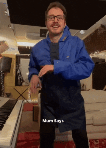 a man in a blue jacket is standing in front of a piano and mum says