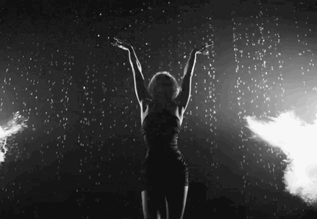 a black and white photo of a woman dancing in the dark