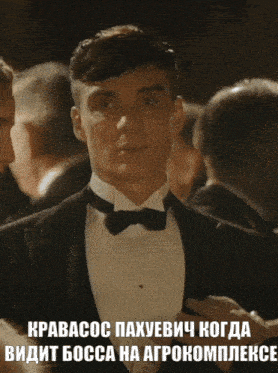 a man in a tuxedo stands in a crowd with a caption in a foreign language