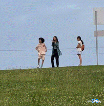 a group of people standing on top of a grassy hill with a sign that says imgplay