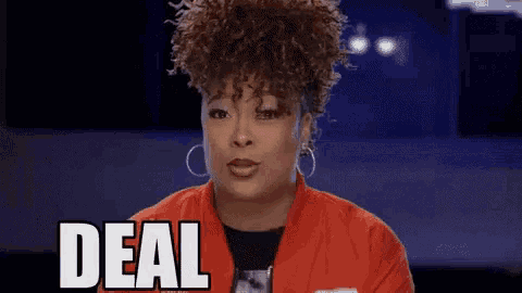 a woman with curly hair is sitting in front of a blue screen and says `` deal with '' .