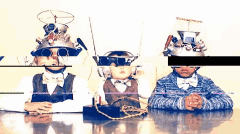 three children are sitting at a table with their faces obscured by objects
