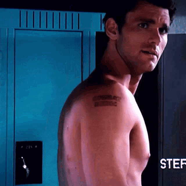 a shirtless man with a tattoo on his shoulder is standing in front of a locker with the name stef on it