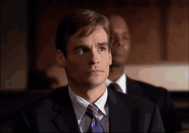 a man in a suit and tie is looking at something