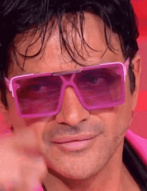 a man is wearing a pair of pink sunglasses and pointing at the camera .