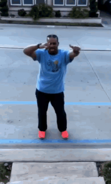 a man wearing a blue shirt that says ohio is dancing in a parking lot