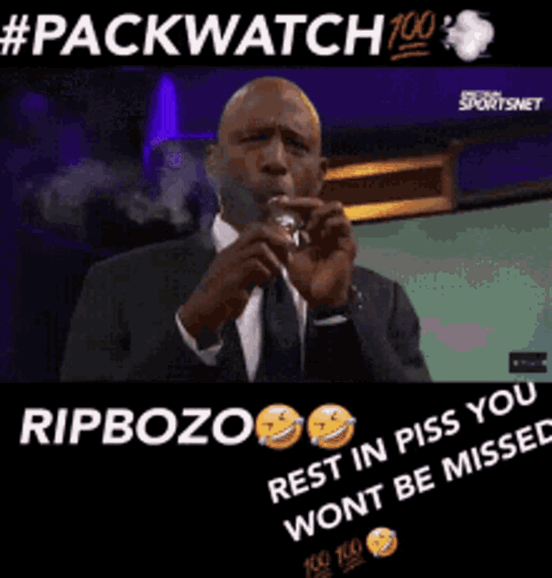 a man in a suit and tie is smoking a cigarette while talking into a microphone ..