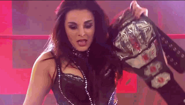 a female wrestler is holding a championship belt over her head