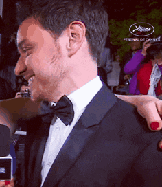 a man in a suit and bow tie is being interviewed by a woman