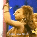 a woman is dancing in front of a wall and says `` baby im a thug '' .
