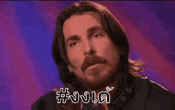a man with long hair and a beard is making a funny face with a purple background